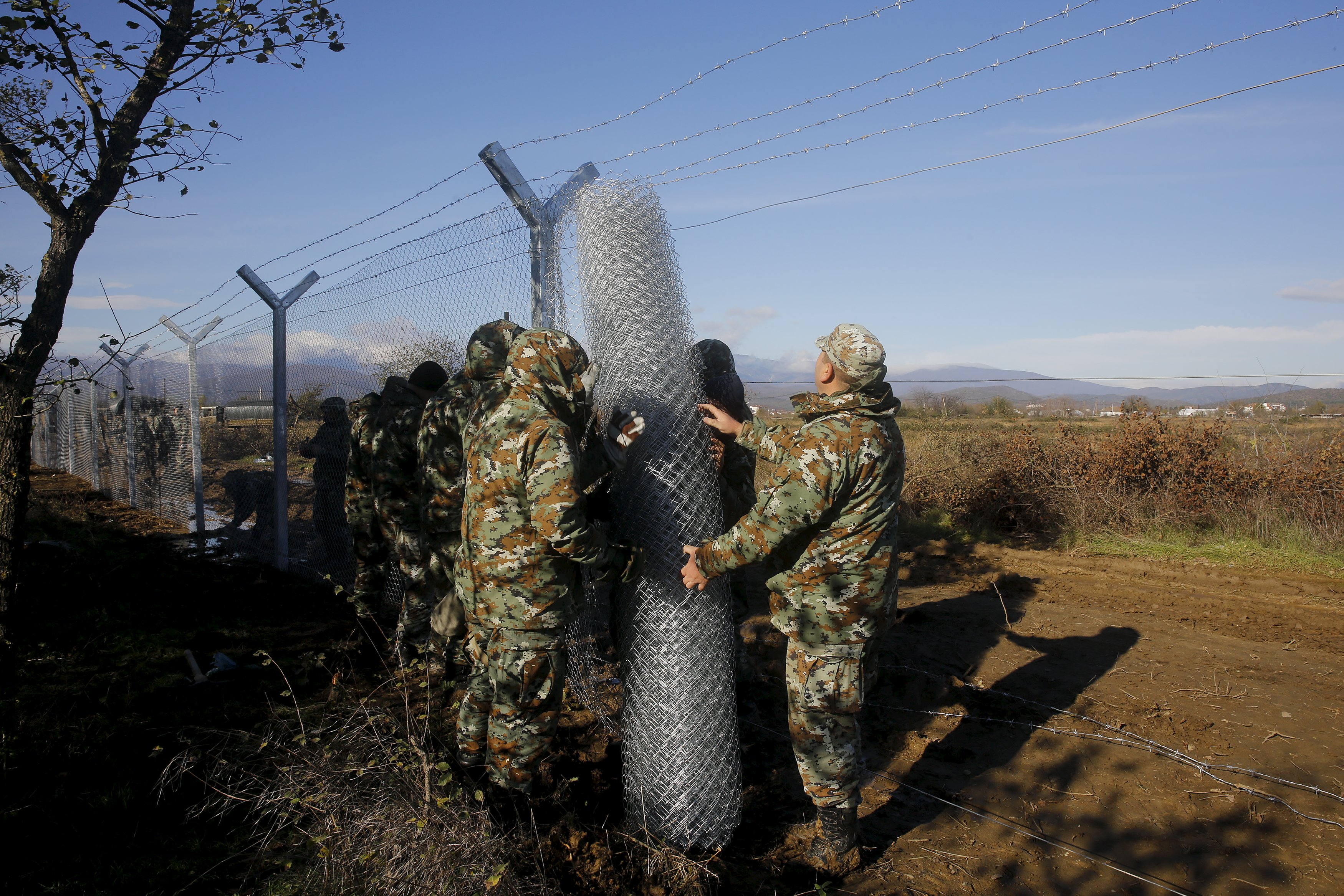 Macedonian soldiers build up a metal fence at the Greek-Macedonian border near the Greek village of Idomeni, November 28, 2015. Soldiers in Macedonia began erecting a metal fence on Saturday on the country's southern border with Greece, described by an official as a "preventive" measure to better control the flow of migrants across the Balkans. Picture taken from the Greek side of the border. REUTERS/Yannis Behrakis