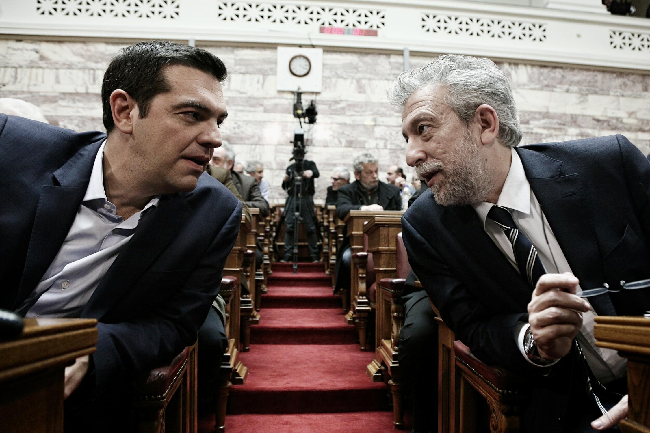 Greek Prime Minister Alexis Tsipras (L) talks with Deputy Minister of Sports Stavros Kontonis (R) at the parliament prior to deliver a speech to his parliamentary group in Athens, Greece on February 17, 2015.