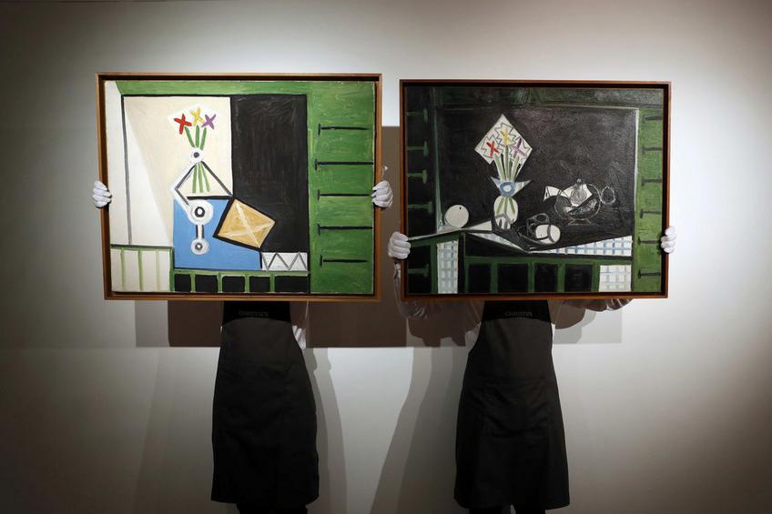 Art handlers pose with "Nature morte" and "Nature morte aux volets verts" by Pablo Picasso at Christie's auction house in London